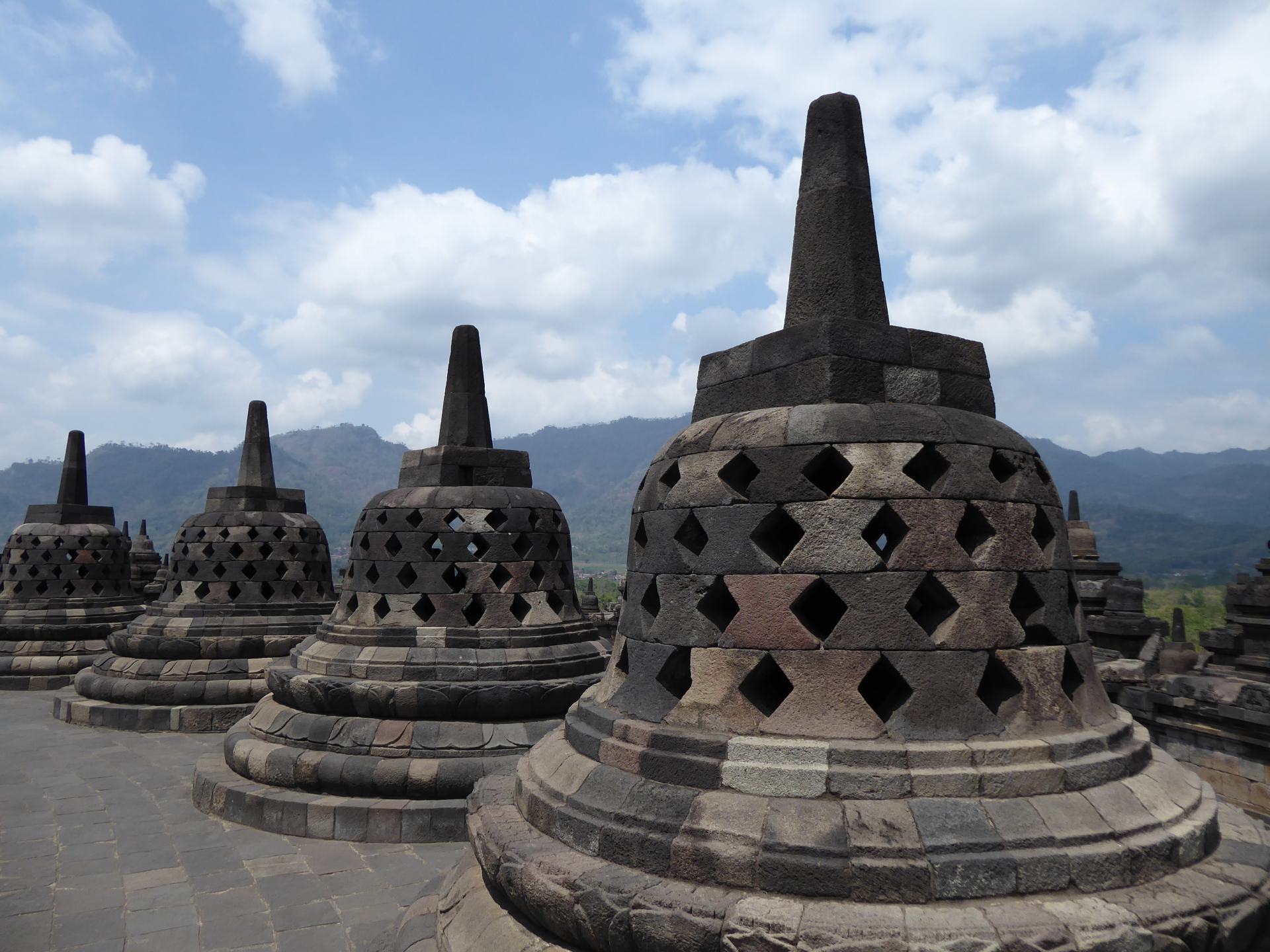 4 Stupas at Borobudur Temple on Java, Indonesia. You can see hills and mountains in the distance. 